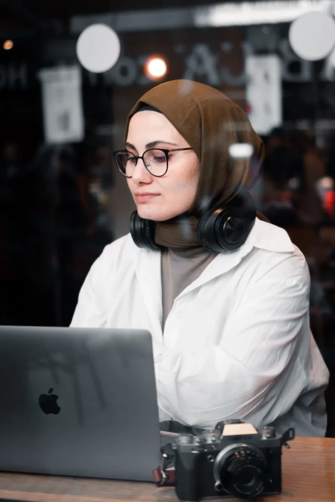 AI copywriting website, perempuan berhijab menyunting teks di laptop