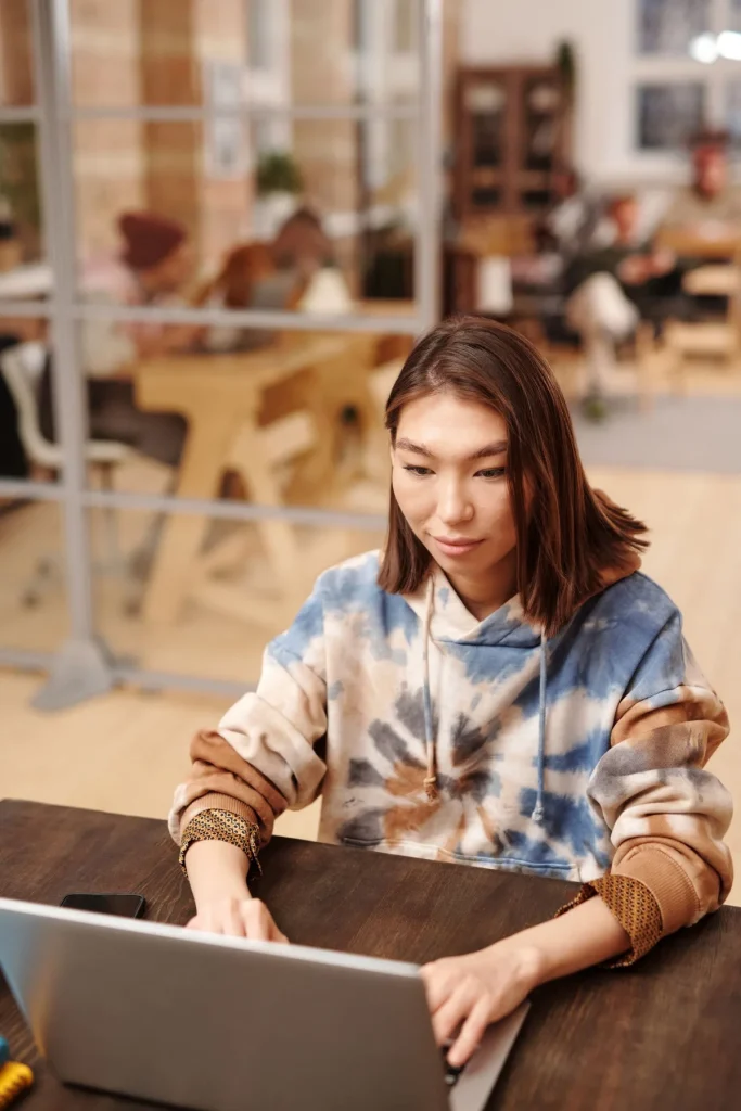 AI website builder vs website builder, perempuan membandingkan di laptop coworking