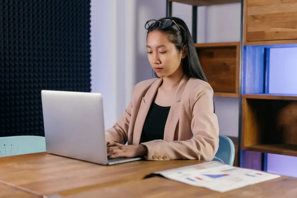 Membuat website dengan AI, perempuan mengetik prompt di laptop kantor