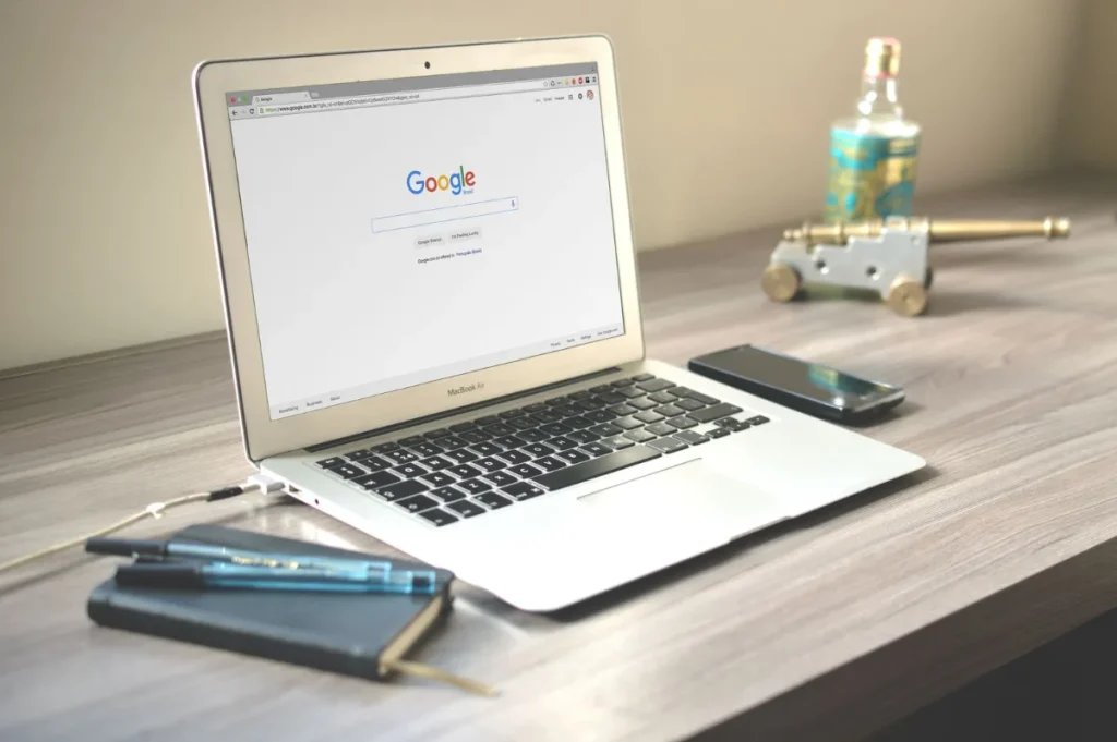 Laptop menampilkan halaman pencarian Google di meja kerja